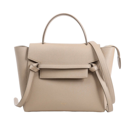 CELINE Belt Bag Micro 2Way Handbag in beige grained leather, showcasing a structured design with a top handle, knotted front belt detail, winged sides, and a detachable shoulder strap, displayed against a white background.
