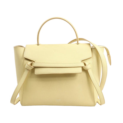 Front view of a CELINE Belt Bag Micro in yellow grained leather featuring a structured body, front flap with signature belt detail, top handle, and an adjustable shoulder strap for 2-way carrying.