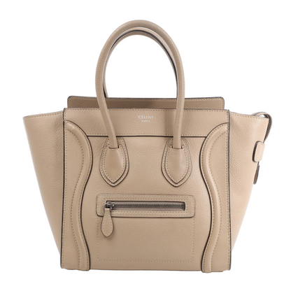 Celine Luggage Micro Handbag in beige grained leather with dual top handles, a front zip pocket, and curved stitched detailing, photographed upright against a white background.