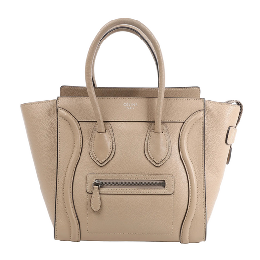 Celine Luggage Micro Handbag in beige grained leather with dual top handles, a front zip pocket, and curved stitched detailing, photographed upright against a white background.