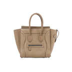 Front view of Celine Luggage Micro beige grained leather handbag with flared sides, rounded top handles, curved leather trim and a front zip pocket.