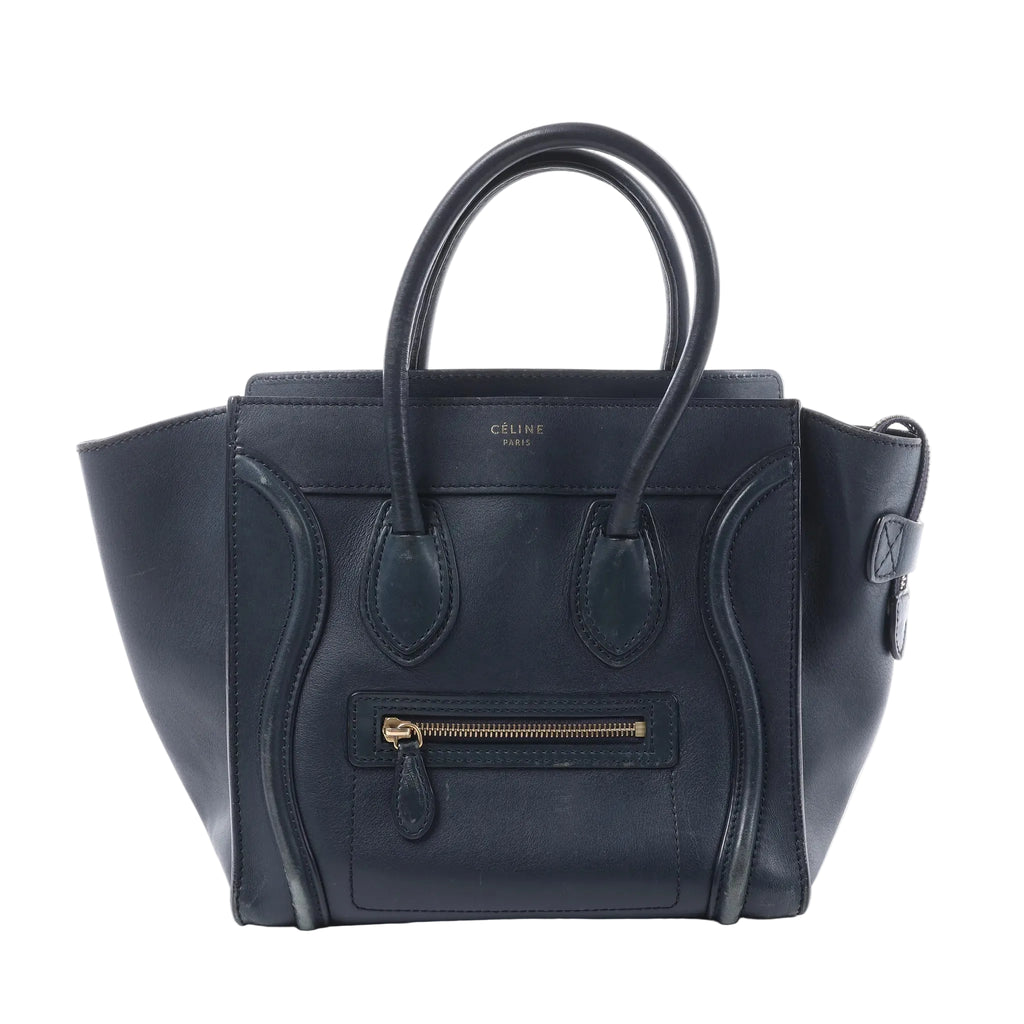 Front view of a navy blue Celine Luggage Micro leather handbag with winged sides, rolled top handles and a gold-tone front zip pocket.