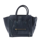 Front view of a navy blue Celine Luggage Micro leather handbag with winged sides, rolled top handles and a gold-tone front zip pocket.
