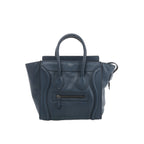 Front view of Celine Luggage Micro navy blue grained leather handbag with flared sides, rounded handles, curved leather trim and a front zip pocket.