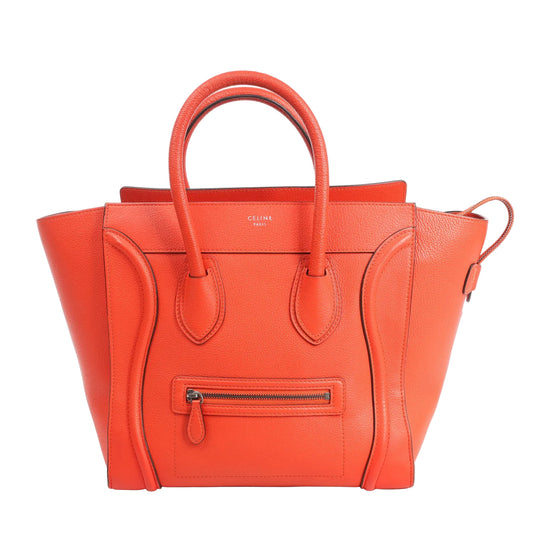 Celine Luggage Mini handbag in bright orange grained leather featuring a structured silhouette with signature winged sides, double top handles, front zip pocket, and minimalist gold logo stamp.