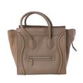 Celine Luggage Micro brown leather handbag with double top handles, winged sides, curved piping, gold-tone logo and front zip pocket.