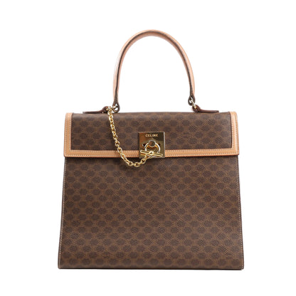 Front view of a Celine Macadam handbag in brown PVC canvas with tan leather trim, gold-tone chain and lock hardware, and a top handle against a white background.