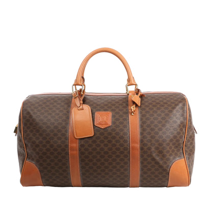 Celine Macadam Boston travel bag in brown PVC with tan leather trim, dual handles, gold-tone hardware, and structured silhouette.