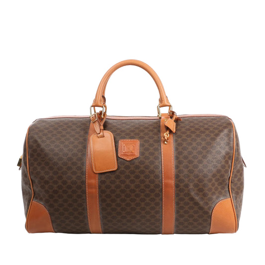 Celine Macadam Boston travel bag in brown PVC with tan leather trim, dual handles, gold-tone hardware, and structured silhouette.