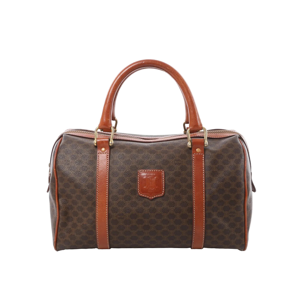 Front view of Celine Macadam Boston brown monogram PVC handbag with tan leather top handles, leather trim, zip-top closure, and front logo patch on a white background.