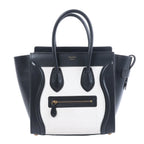 Celine Luggage Micro black and white leather handbag with top handles, winged sides and front zip pocket.