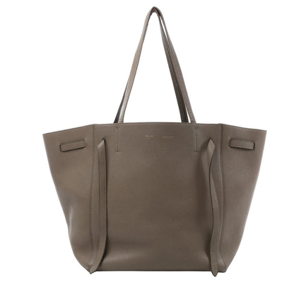 Celine Cabas Phantom Small shoulder bag in taupe grained leather with dual slim handles, open top with tie detail, and structured trapezoid silhouette against a white background.