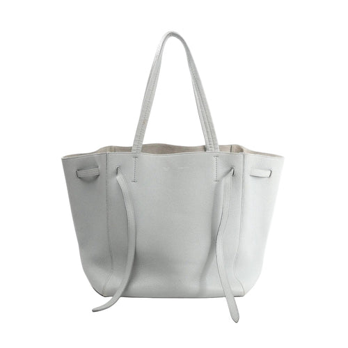Celine Cabas Phantom Small tote in gray pebbled leather with long shoulder straps and side tie details, front view on white background.
