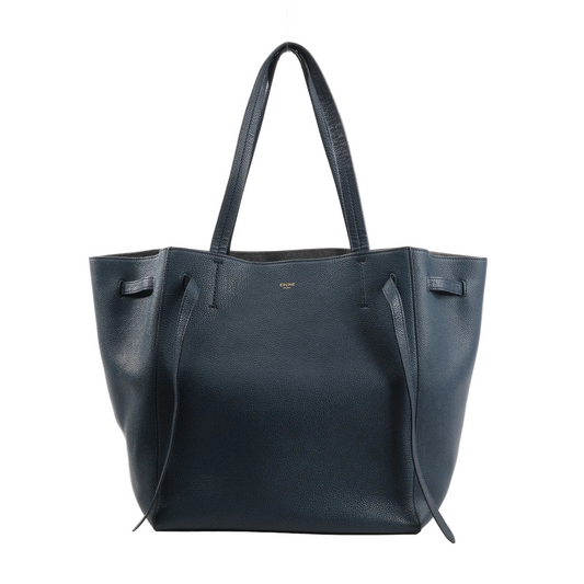 Celine Cabas Phantom Medium Leather Shoulder Bag in navy blue grained calfskin with slim double handles, side leather ties, and open-top design, displayed upright on a white background.