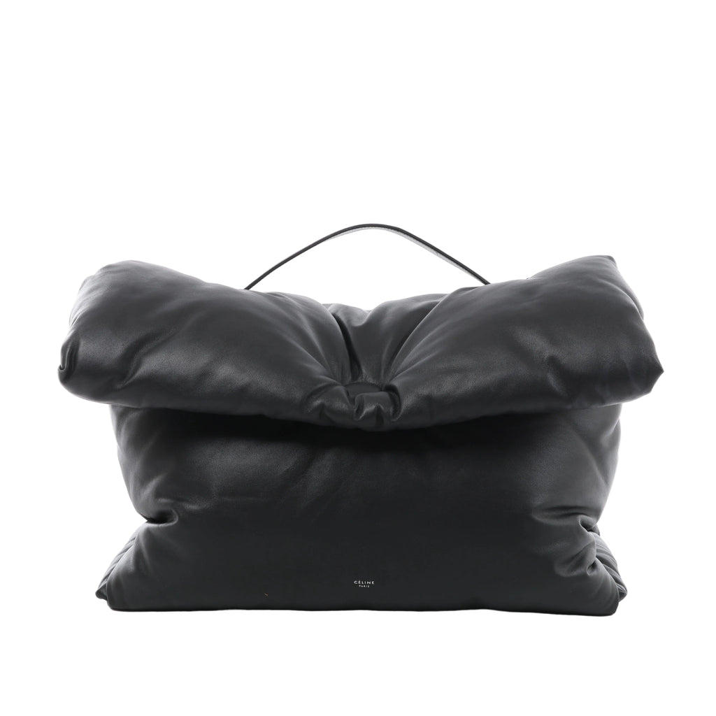 Black Celine Pillow leather handbag with a padded rectangular shape, oversized folded flap, slim top handle and small Celine Paris logo near the base.