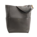 CELINE Seau Sangle Bucket Shoulder Bag in gray grained leather with a wide strap, gold-tone hardware, and subtle logo embossing, standing upright against a white background.