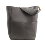 CELINE Seau Sangle Bucket Shoulder Bag in gray grained leather with a wide strap, gold-tone hardware, and subtle logo embossing, standing upright against a white background.