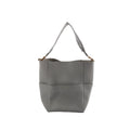 CELINE Seau Sangle bucket shoulder bag in gray pebbled leather with wide fabric shoulder strap and gold-tone hardware on a white background.