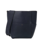 Front view of CELINE Seau Sangle Bucket Leather Shoulder Bag in navy blue, featuring pebbled leather texture, wide adjustable fabric shoulder strap, and subtle gold CELINE Paris logo against a white background.