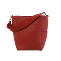 CELINE Seau Sangle bucket shoulder bag in red grained leather with a wide matching shoulder strap, gold-tone hardware and minimalist design on a white background.