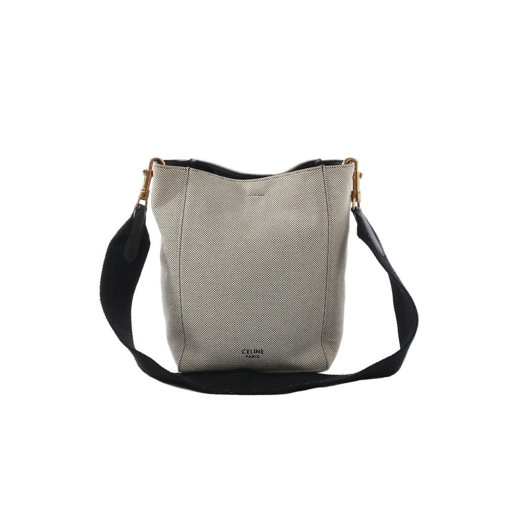 Celine Seau Sangle small beige canvas bucket bag with navy shoulder strap, gold-tone hardware, and Celine logo on white background.