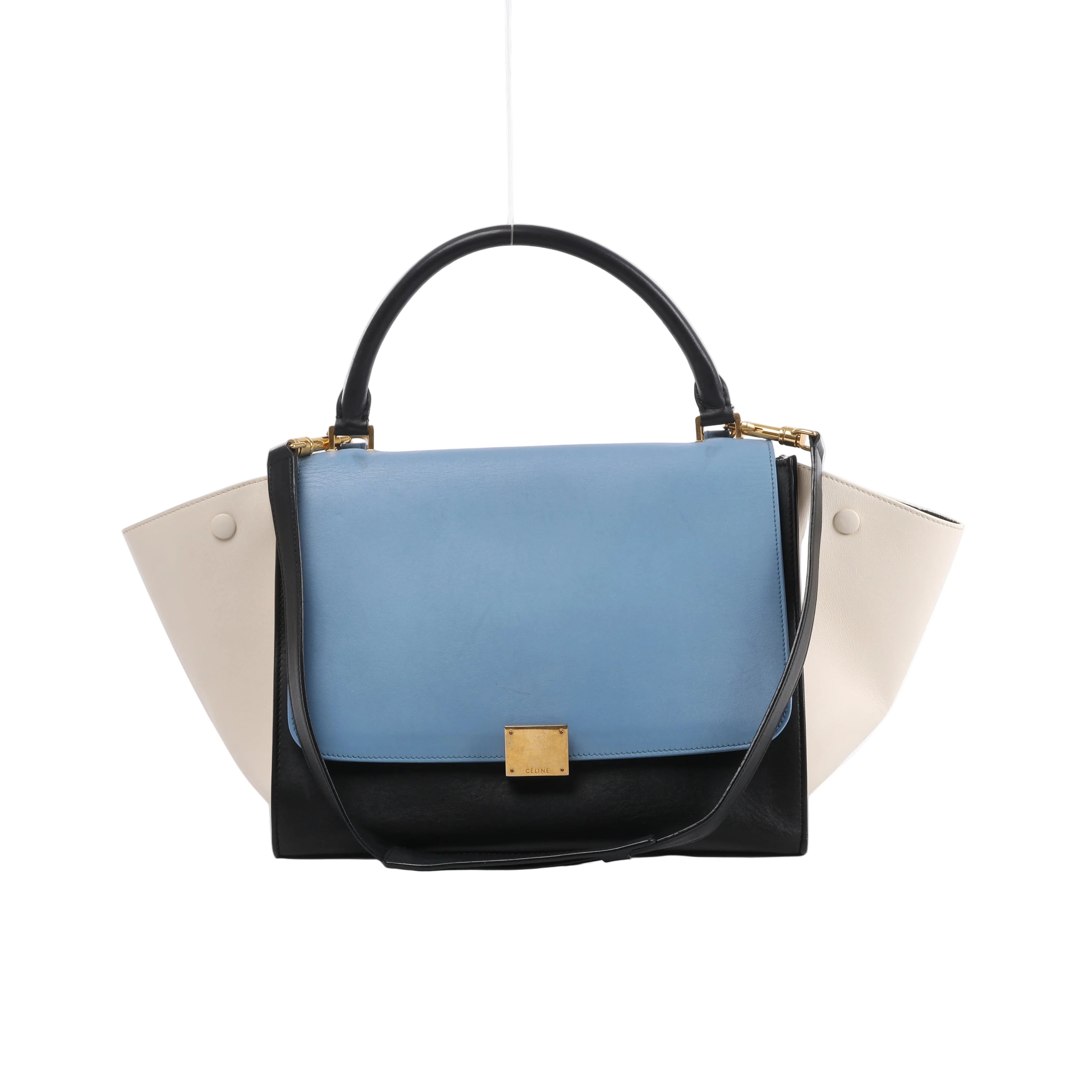 Celine Trapeze leather handbag with sky blue flap, white winged sides, black body and top handle, shoulder strap and gold-tone clasp hardware.