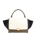 CELINE Trapeze 2Way handbag in beige leather with black suede side wings, khaki green base, top handle, and gold-tone front clasp, structured with modern elegance.