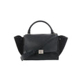 Black Celine Trapeze handbag in leather and suede with top handle, front flap, silver-tone clasp, side panels, and shoulder strap on a white background