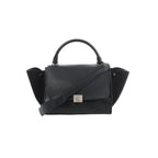 Black Celine Trapeze handbag in leather and suede with top handle, front flap, silver-tone clasp, side panels, and shoulder strap on a white background