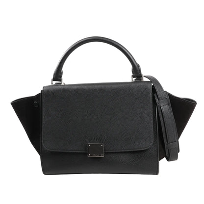 CELINE Trapeze 2Way handbag in black grained leather with suede side wings, featuring a structured flap front, top handle, detachable shoulder strap, and silver-tone hardware.