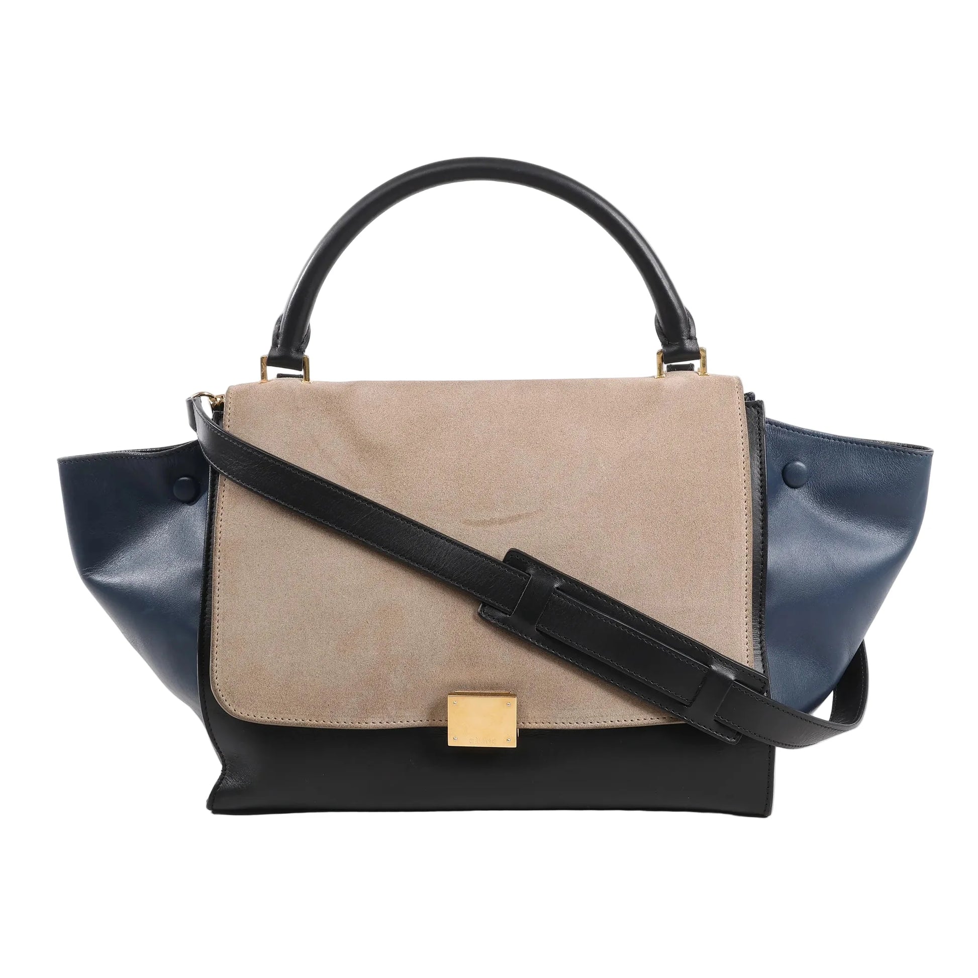 CELINE Trapeze 2Way Handbag in black, navy, and taupe, featuring a taupe suede flap, navy leather side wings, black leather body and top handle, gold-tone square clasp, and detachable black shoulder strap, displayed on a white background.