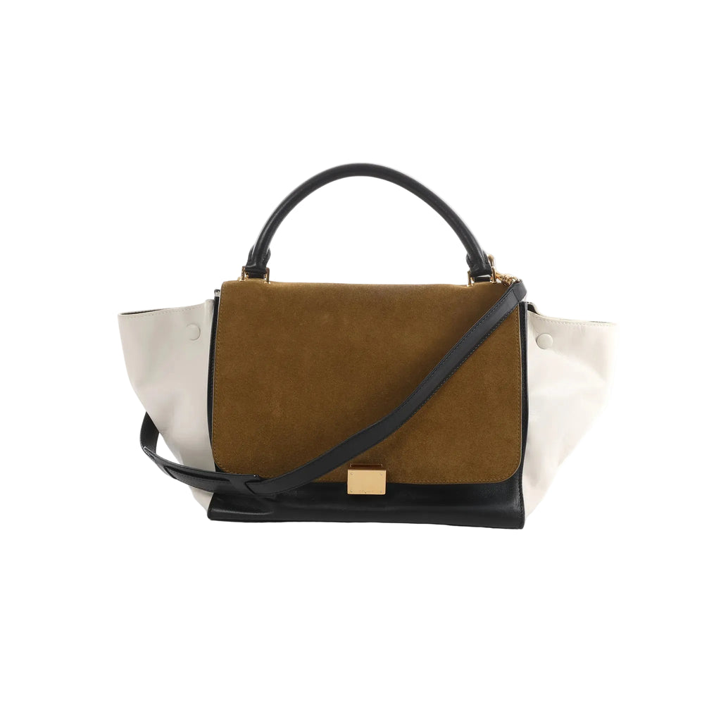 Celine Trapeze handbag with brown suede front flap, white leather side panels, black leather base and handle, gold clasp, and black strap on white background