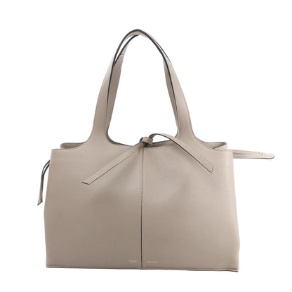 Celine Tri-Fold Shoulder Bag in smooth greige leather with dual slim handles, tie detail at the top, and structured rectangular silhouette against a white background.
