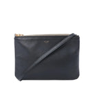 Celine Trio Small black leather crossbody bag with slim shoulder strap, gold-tone zip closure, and small Celine Paris logo on white background.