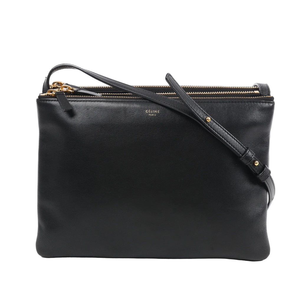 Front view of the Celine Trio Large Leather Crossbody Bag in black, showcasing smooth black calfskin leather, gold-tone zippers, an adjustable leather shoulder strap, and subtle Celine Paris branding, all set against a white background.