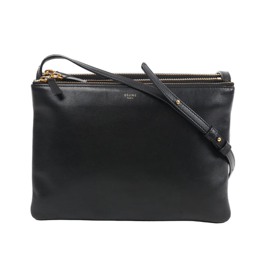 Front view of the Celine Trio Large Leather Crossbody Bag in black, showcasing smooth black calfskin leather, gold-tone zippers, an adjustable leather shoulder strap, and subtle Celine Paris branding, all set against a white background.