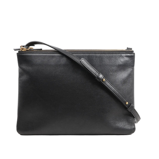 Front view of a Celine Trio Large Crossbody Bag in smooth black leather featuring a clean rectangular silhouette, adjustable leather shoulder strap with gold-tone hardware, and multiple zippered compartments.