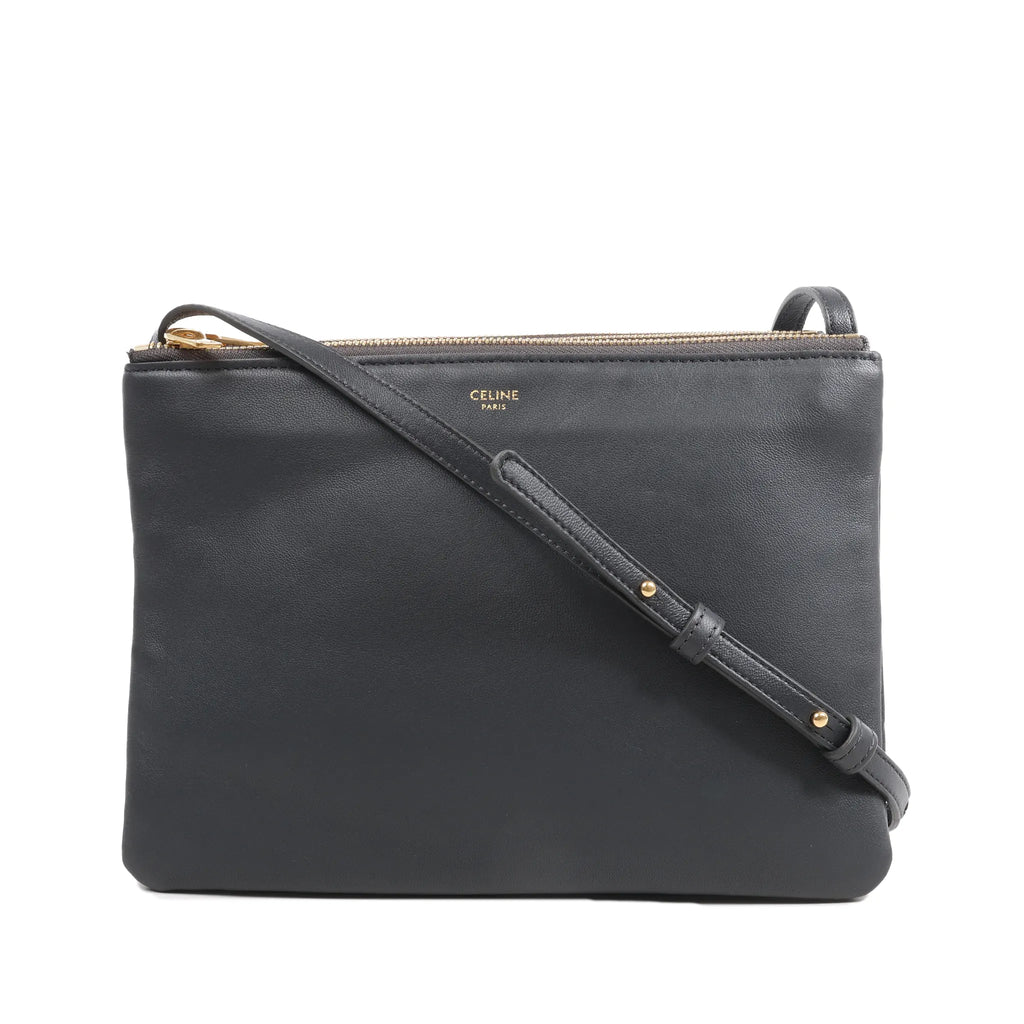 Black Celine Trio Large leather crossbody bag with slim shoulder strap, gold-tone top zip closure, and Celine Paris logo on front.