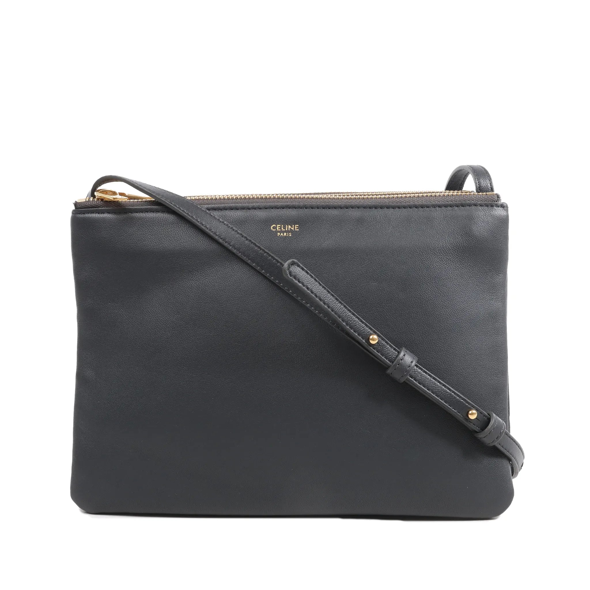 Black Celine Trio Large leather crossbody bag with slim shoulder strap, gold-tone top zip closure, and Celine Paris logo on front.