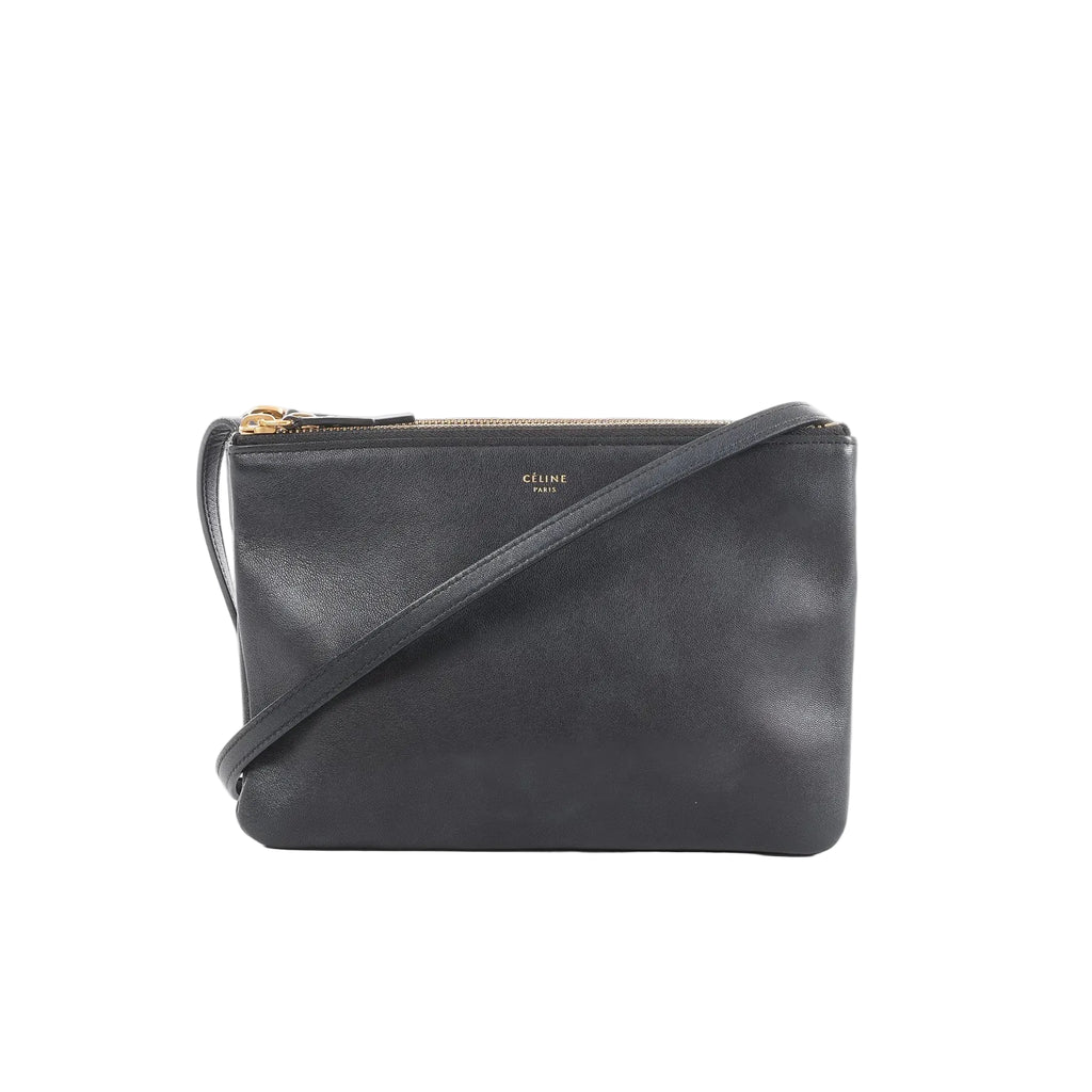 Black Celine Trio Small leather crossbody bag with zip-top closure, slim strap, and small gold logo on a white background