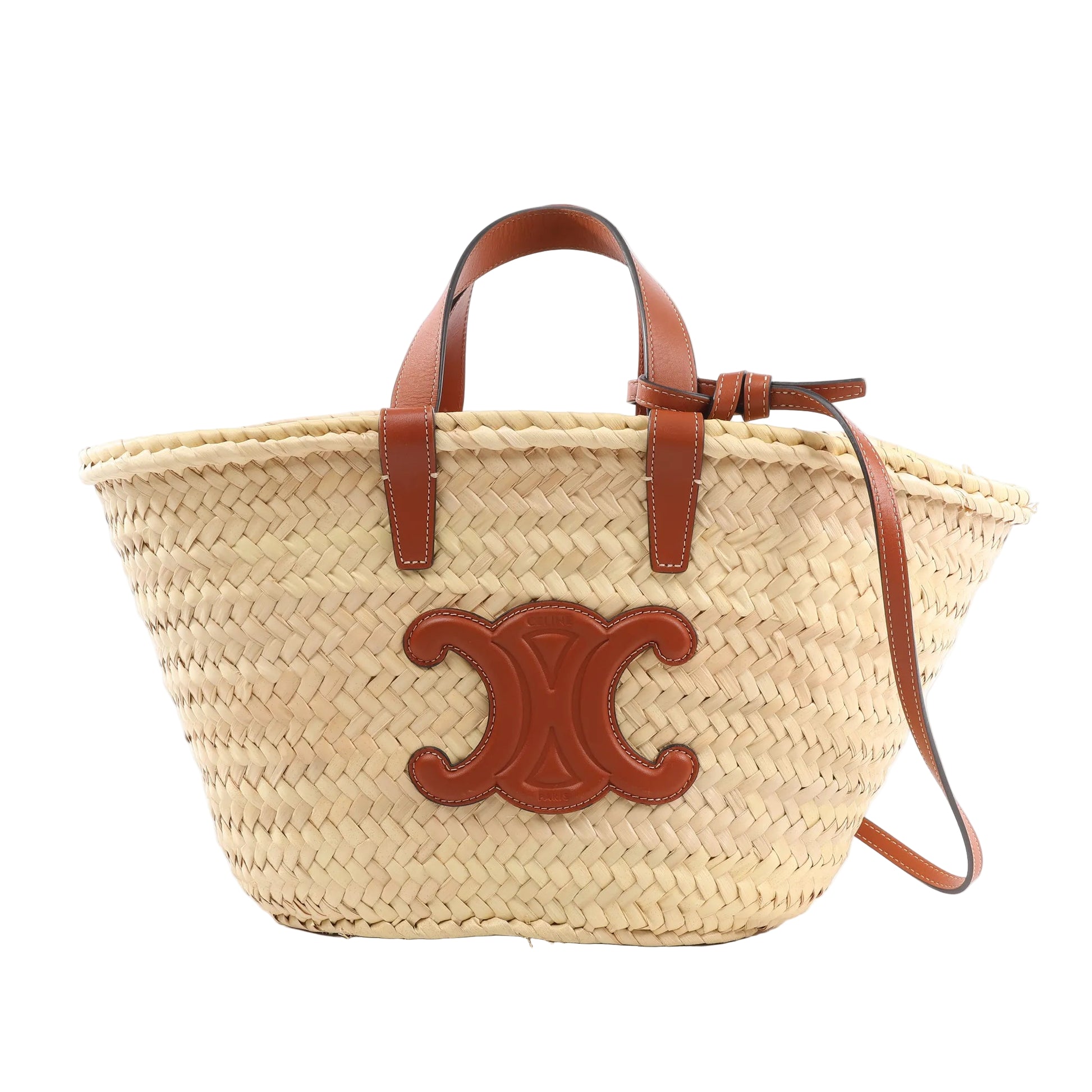 Celine Triomphe handbag made of woven beige straw with brown leather top handles, crossbody strap, and large leather Triomphe logo patch on the front, displayed against a white background.
