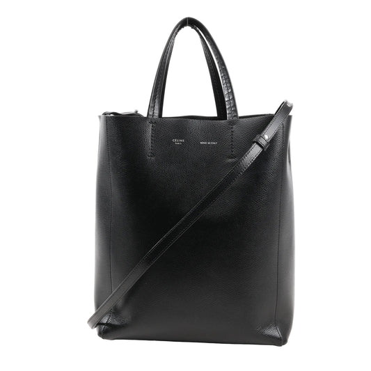 CELINE Cabas Vertical Small handbag in black grained leather with top handles, slim crossbody strap, and minimalist silver branding on front.
