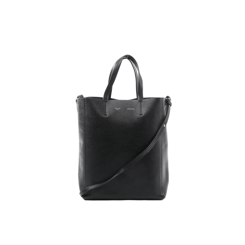 Black textured leather CELINE Cabas Vertical Small tote with two top handles and a long shoulder strap, front view on a white background.