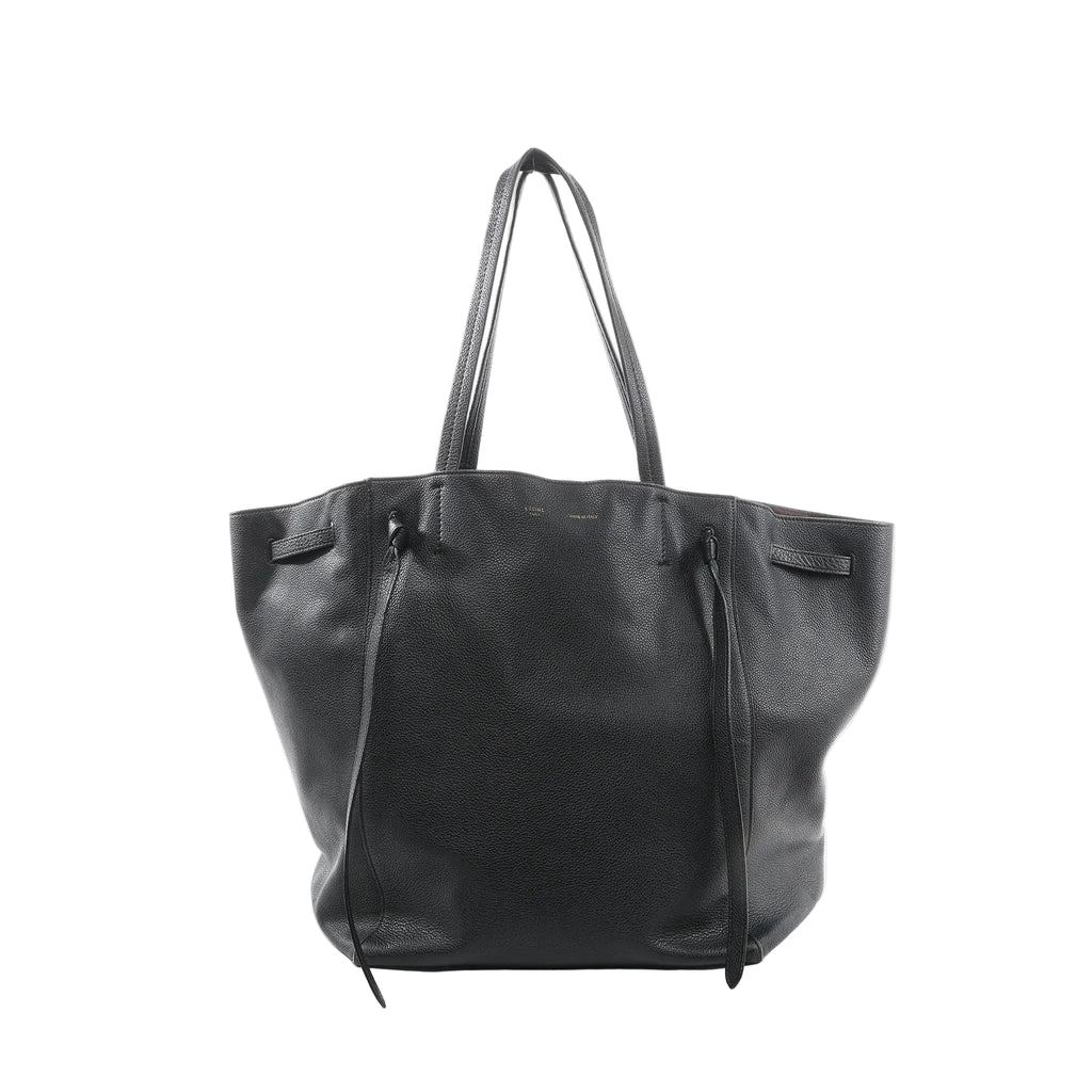 Black Celine Cabas Phantom Medium leather shoulder tote with two long top handles, open-top silhouette, and front panel with knotted leather tie details, shown on a white background.