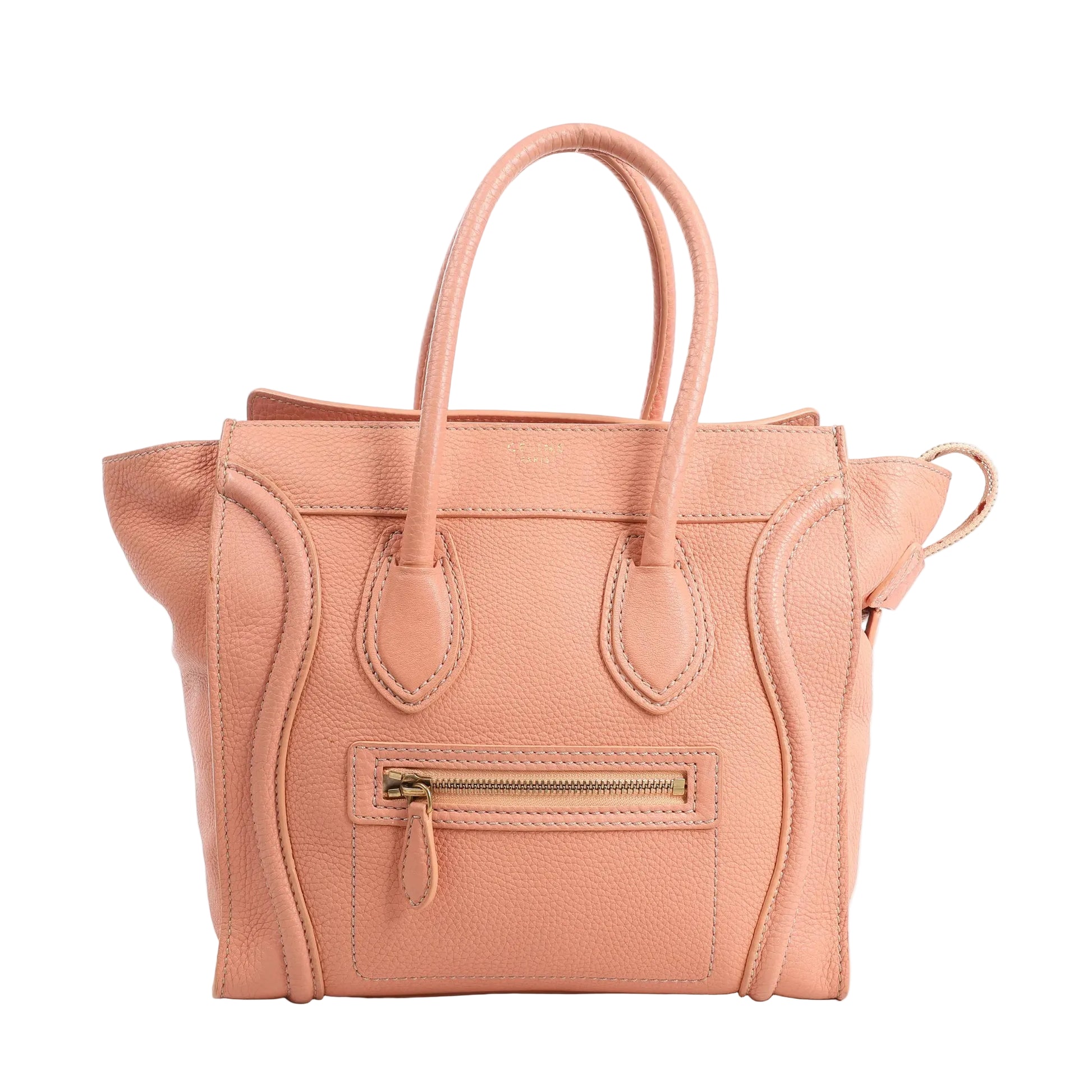 Front view of a CELINE Luggage Micro handbag in pink grained leather, featuring double top handles, front zip pocket, curved stitched detailing, and a structured silhouette.