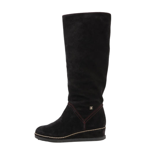 Chanel Coco Mark Chain 15B long boots in black suede, featuring a hidden wedge heel, gold-tone chain trim along the sole, red stitching, and small gold CC logo on the side. Size 36 EU.