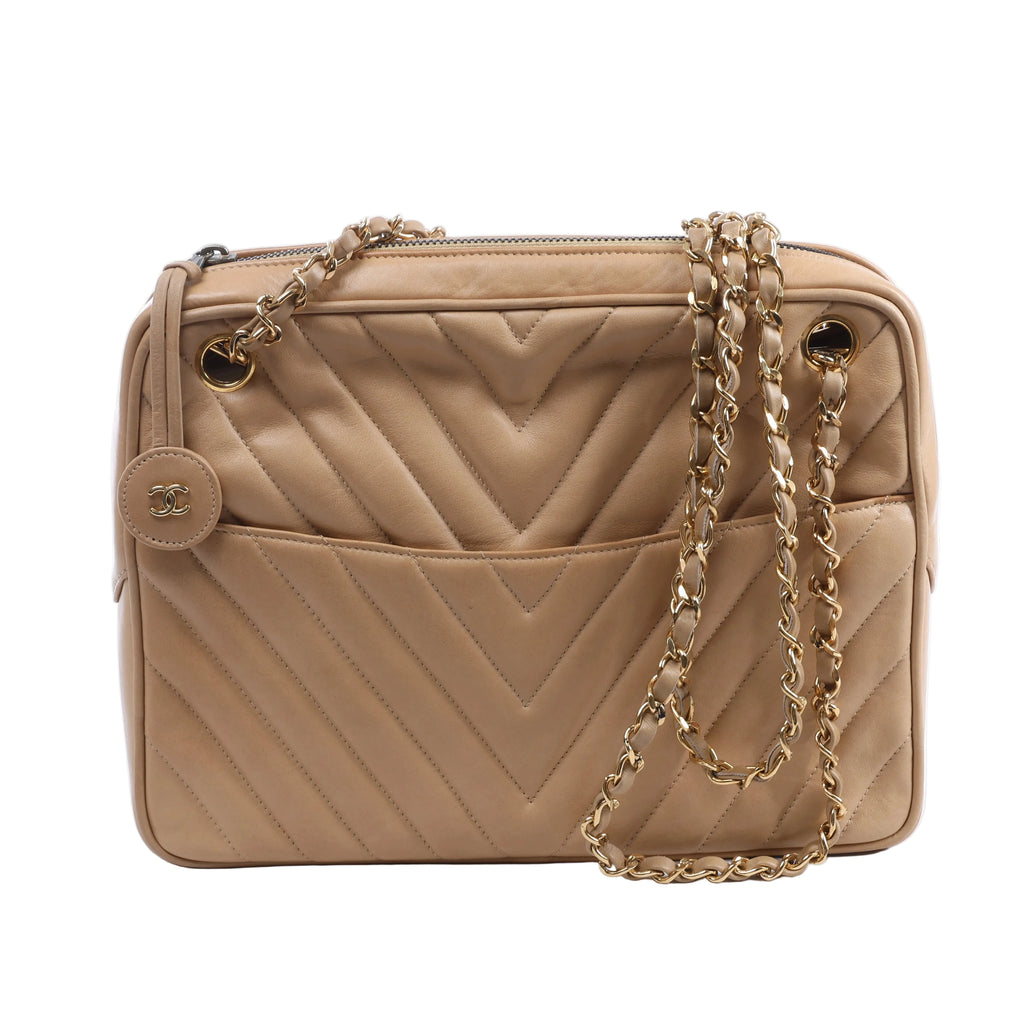 Beige Chanel leather shoulder bag with chevron quilting, gold-tone chain straps, top zip closure and round CC charm.
