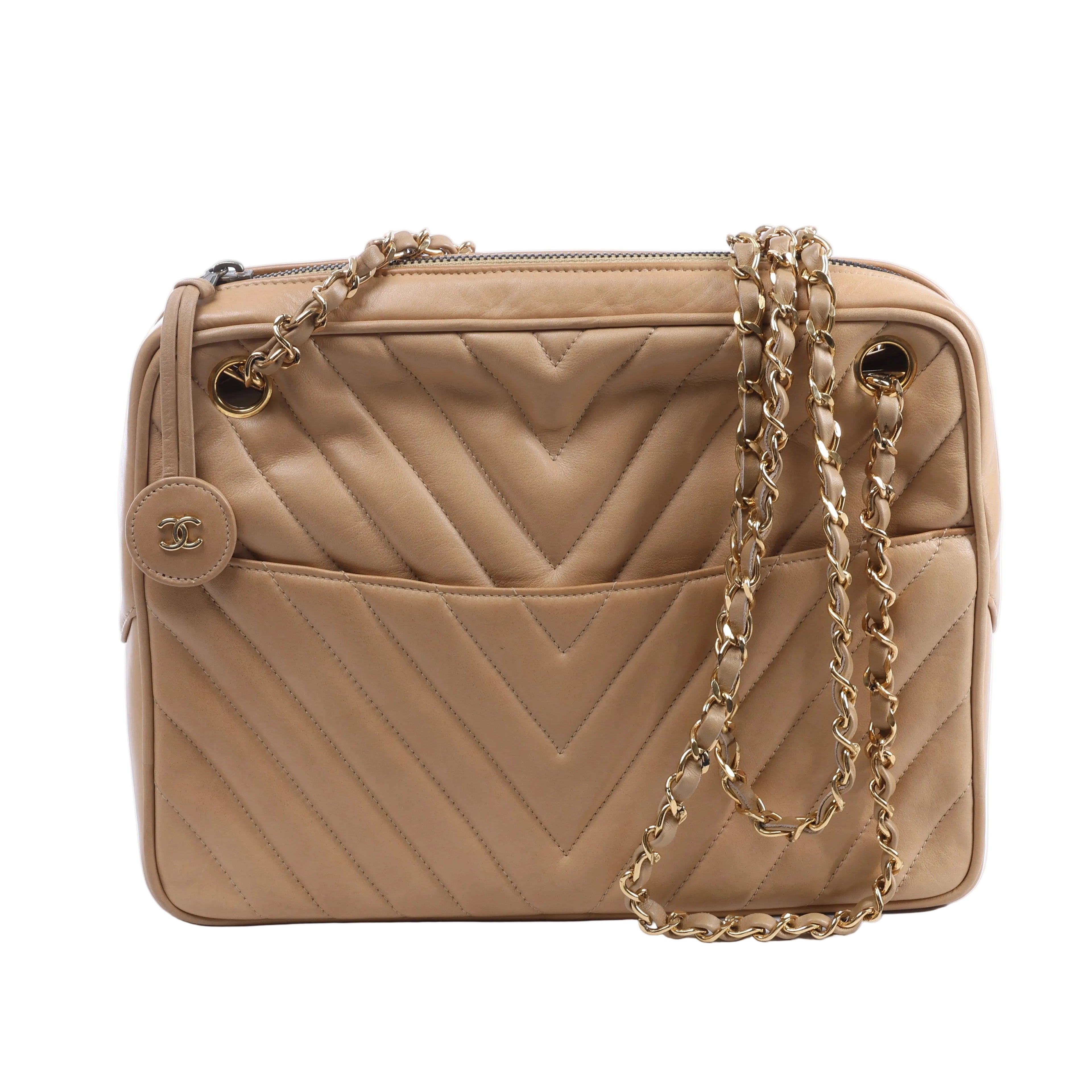 Beige Chanel leather shoulder bag with chevron quilting, gold-tone chain straps, top zip closure and round CC charm.