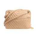 Front view of a Chanel Chevron shoulder bag in beige leather featuring V-quilted stitching, a long leather shoulder strap, external slip pocket, and gold-tone hardware with signature CC charm zipper pull.