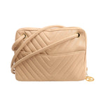 Front view of a Chanel Chevron shoulder bag in beige leather featuring V-quilted stitching, a long leather shoulder strap, external slip pocket, and gold-tone hardware with signature CC charm zipper pull.